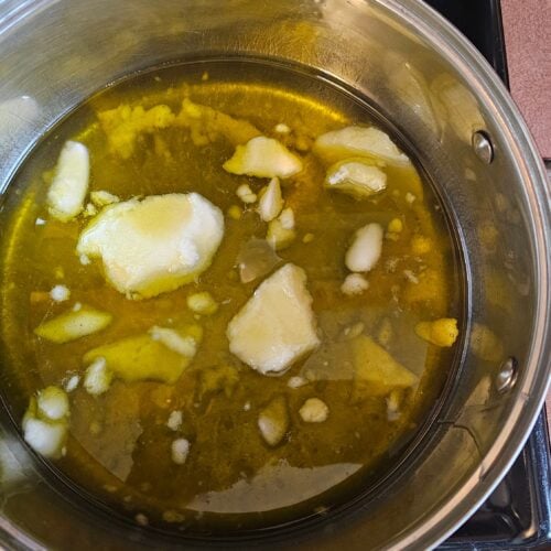 melting solid oils in a stainless steel pot for making plantain soap
